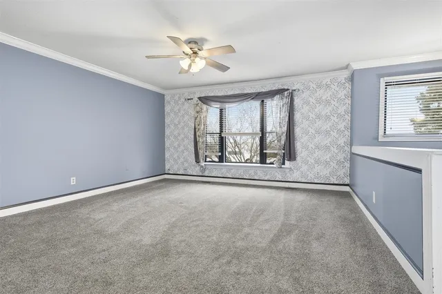 an empty room with windows and chandelier fan