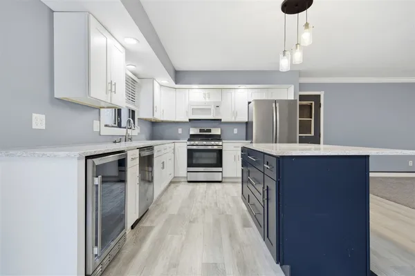 a kitchen with stainless steel appliances kitchen island granite countertop a stove top oven a sink dishwasher a dining table and chairs with wooden floor