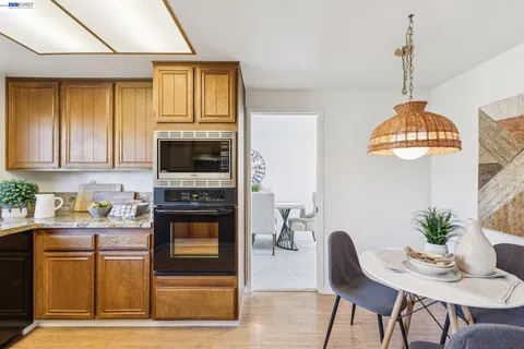 a kitchen with stainless steel appliances granite countertop a stove a sink dishwasher a microwave oven with a dining table and chairs with wooden floor