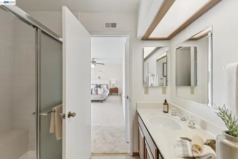 a en suite bathroom with a granite countertop double vanity sink and mirror