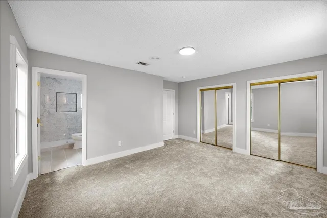 an empty room with mirror and a bathroom