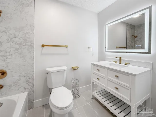 a bathroom with a toilet a sink a mirror a bathtub and vanity