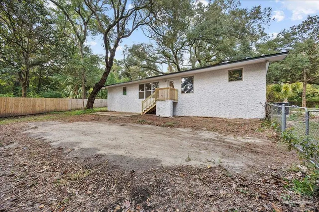 a backyard of a house with large trees and wooden fence