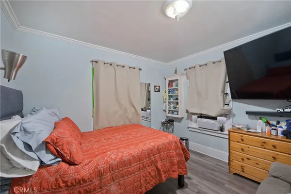 a bedroom with a bed and a flat tv screen on the dresser