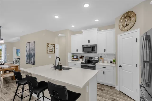 a kitchen with stainless steel appliances a table chairs refrigerator and cabinets