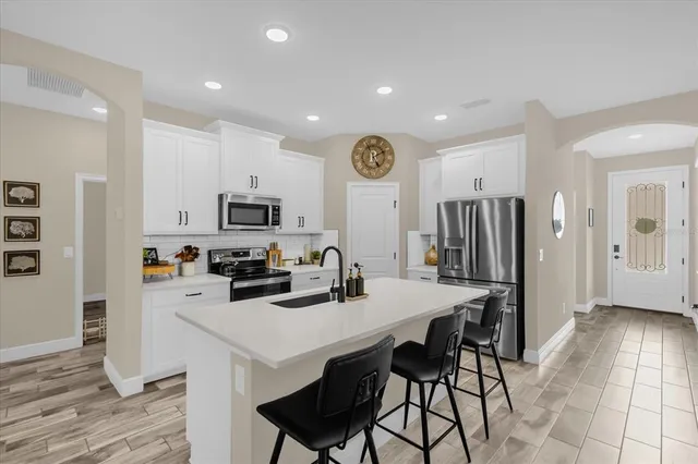 a kitchen with stainless steel appliances a stove a refrigerator a sink a dining table and chairs