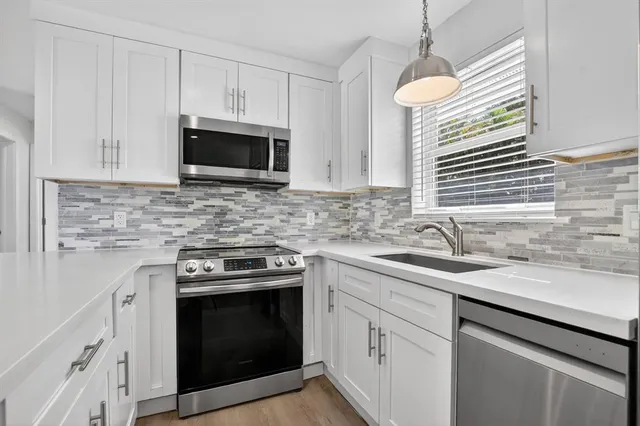 a kitchen with granite countertop a sink stove and microwave