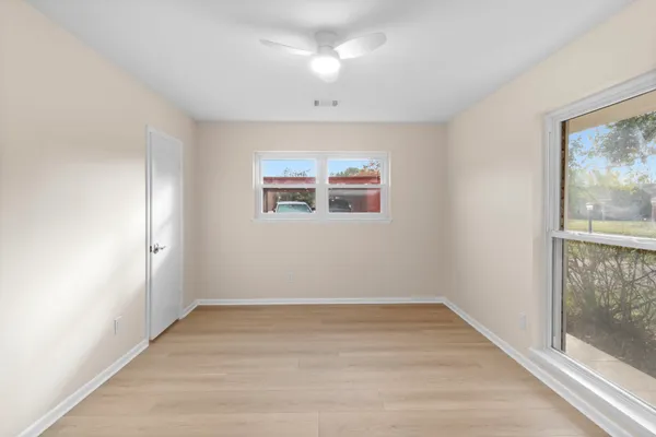 a view of empty room with wooden floor and fan