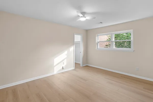 an empty room with wooden floor and windows