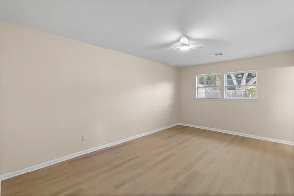 an empty room with wooden floor and windows