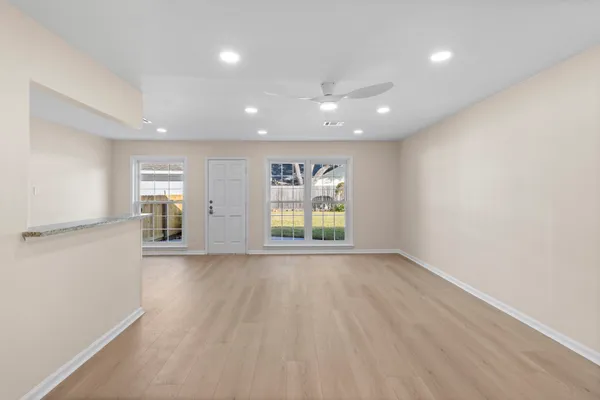 an empty room with wooden floor and windows