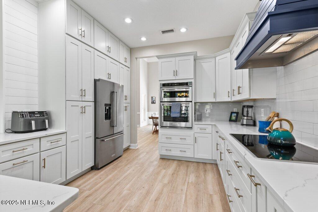 2676 Country Side Drive Fleming Island, FL 32003 - Photo 31 of 125 a kitchen with white cabinets and stainless steel appliances