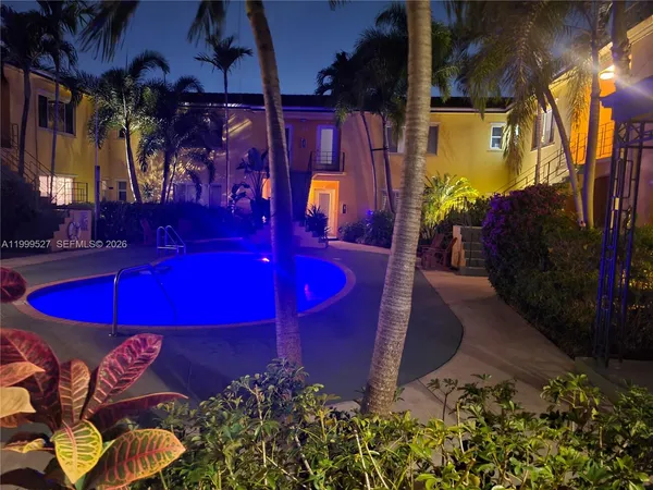 a view of a pool with red chairs in front of building
