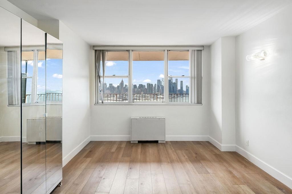 6040 Boulevard East, Unit 22F West New York, NJ 07093 - Photo 18 of 44 a view of an empty room with wooden floor and a window