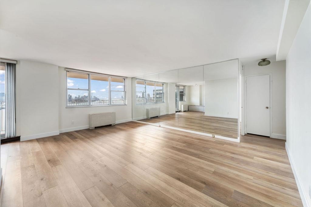 6040 Boulevard East, Unit 22F West New York, NJ 07093 - Photo 2 of 44 an empty room with wooden floor and windows