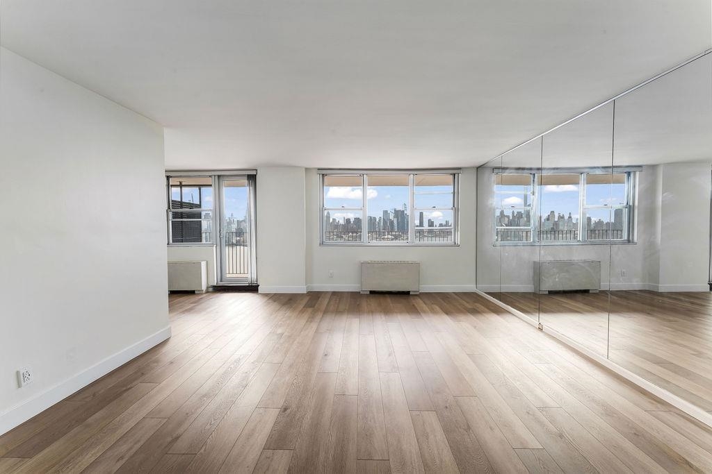 6040 Boulevard East, Unit 22F West New York, NJ 07093 - Photo 4 of 44 an empty room with wooden floor and windows