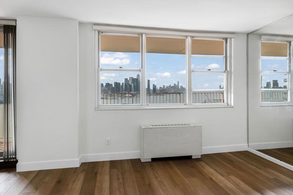6040 Boulevard East, Unit 22F West New York, NJ 07093 - Photo 7 of 44 an empty room with wooden floor and windows