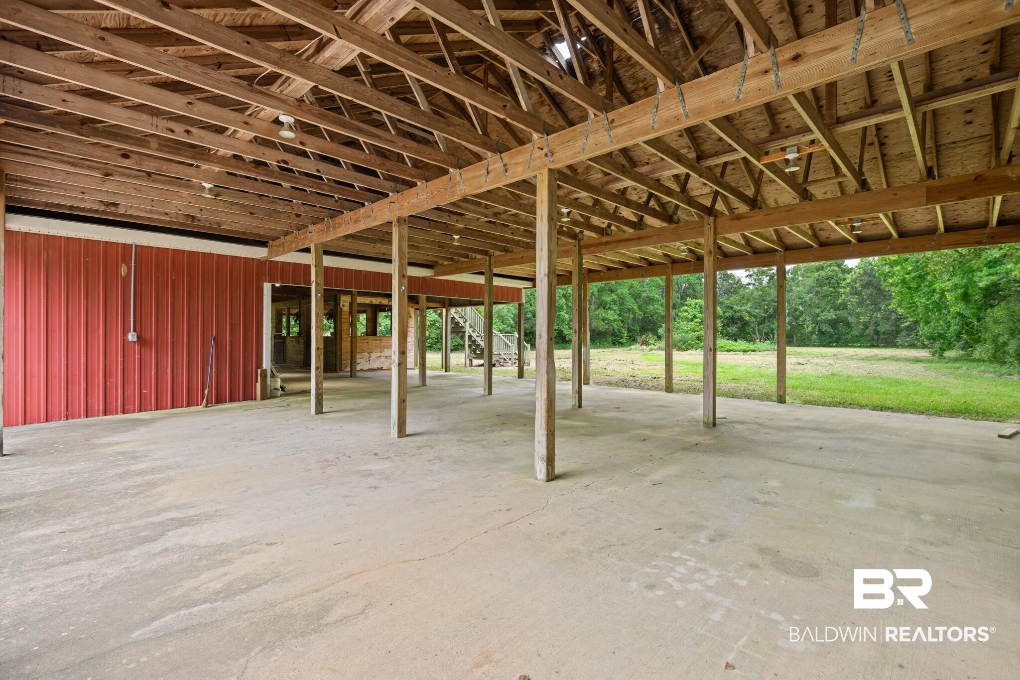 7540 2 Mile Road Irvington, AL 36544 - Photo 65 of 82 Expansive covered structure featuring exposed wood beams, a concrete floor, red metal siding, and integrated lighting