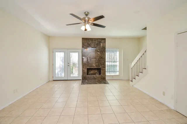 a view of an empty room with chandelier fan and fire place