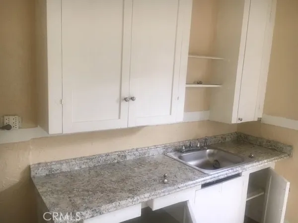 a kitchen with granite countertop a sink and a white cabinets