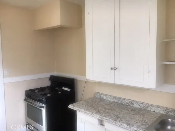 a kitchen with granite countertop white cabinets and black appliances