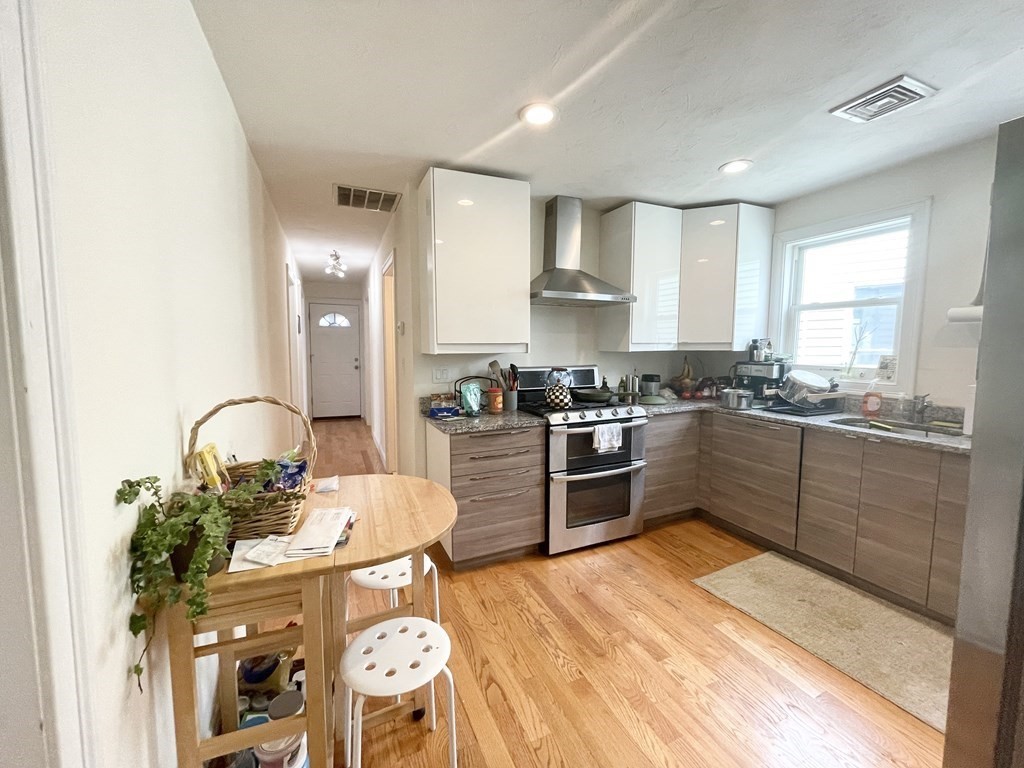a kitchen with stainless steel appliances granite countertop a stove a sink dishwasher and a refrigerator with wooden floor