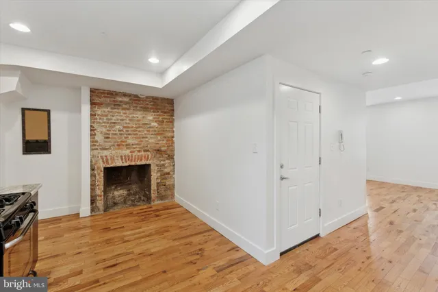 a view of empty room with wooden floor and fireplace