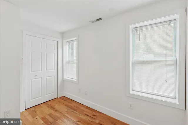 a view of an empty room with wooden floor and closet