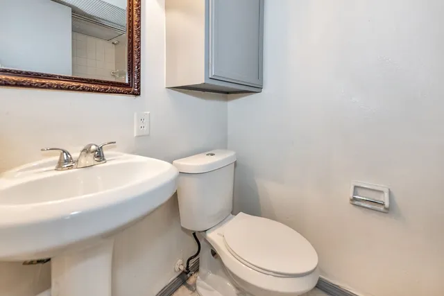 a bathroom with a toilet a sink and mirror