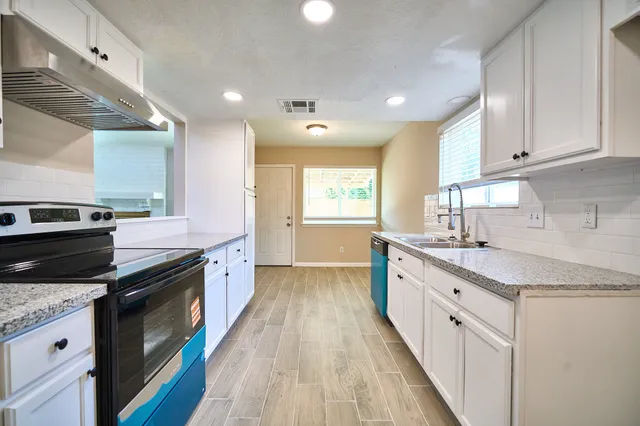 a large kitchen with a granite countertop sink stainless steel appliances and cabinets