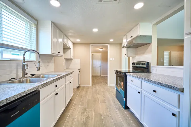 a large kitchen with stainless steel appliances kitchen island granite countertop a large counter top a sink a stove and a window