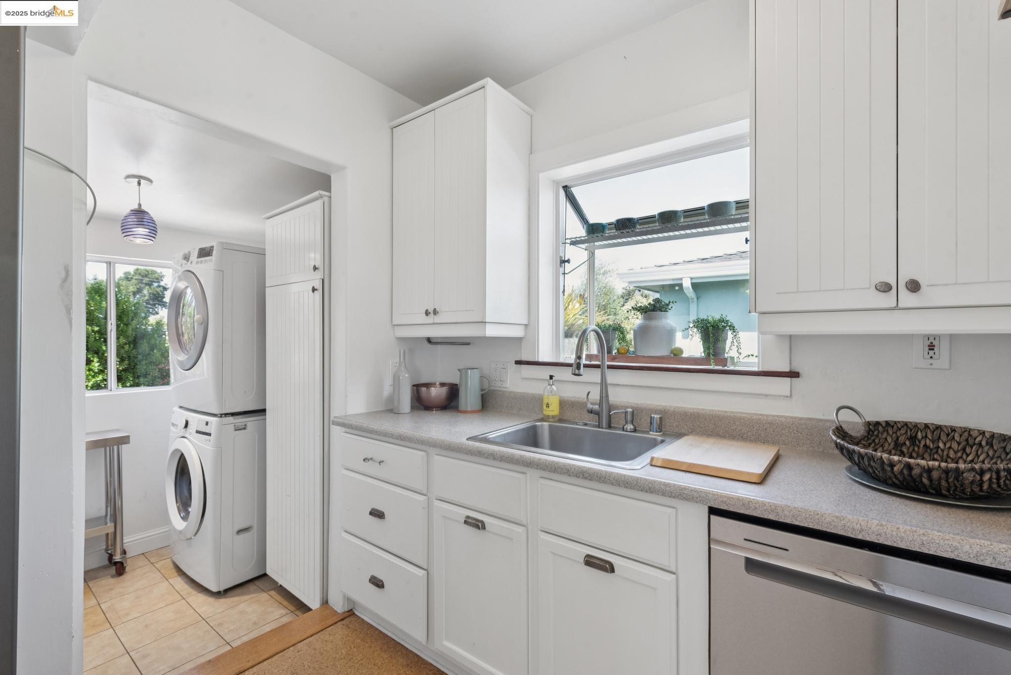 2721 Best Avenue Oakland, CA 94619 - Photo 13 of 28 Laundry area with stacked washer / dryer, plenty of natural light, and light tile patterned flooring
