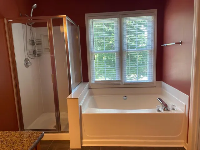 a bathroom with a granite countertop sink a mirror and a bathtub