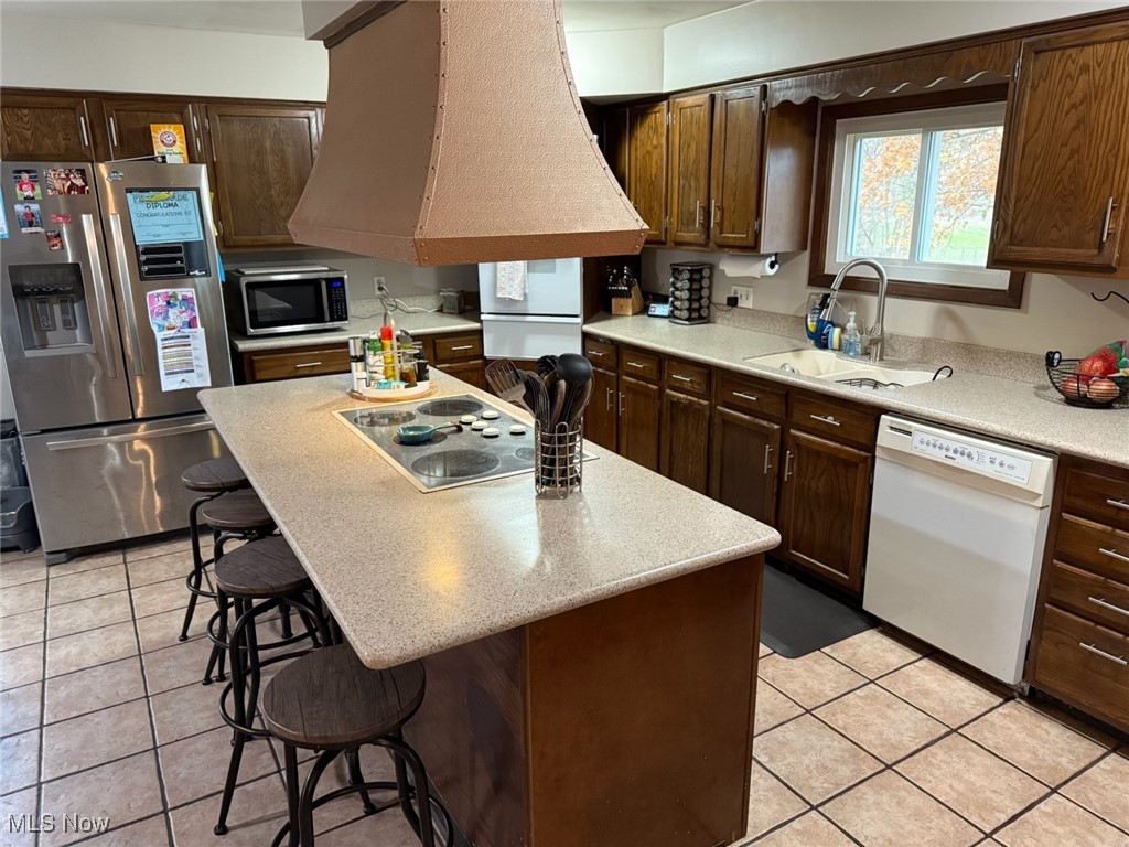 10719 Johnnycake Ridge Road Painesville, OH 44077 - Photo 6 of 21 Kitchen featuring a kitchen breakfast bar, stainless steel appliances, a center island, dark brown cabinets, and light tile patterned floors