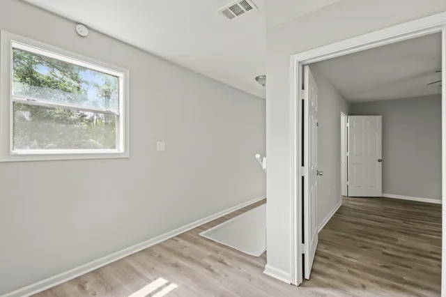 a view of a hallway with wooden floor and a window
