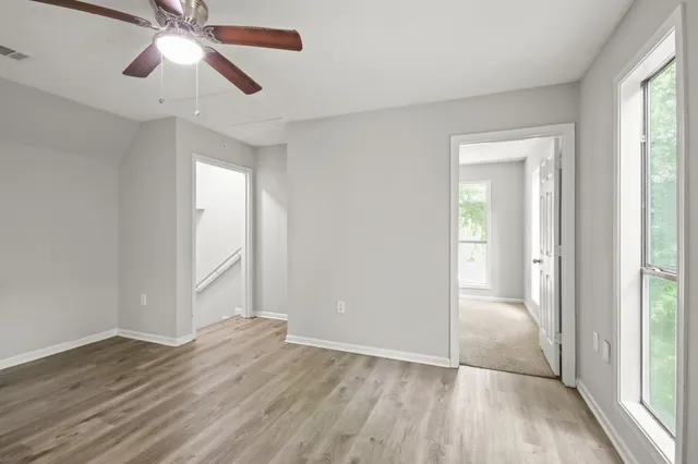a view of empty room with wooden floor and fan