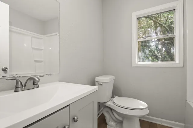 a bathroom with a sink a toilet and a window
