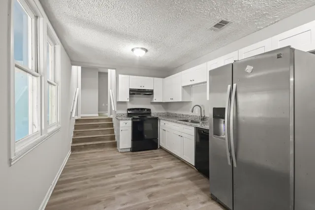 a kitchen with stainless steel appliances granite countertop a refrigerator and a stove top oven