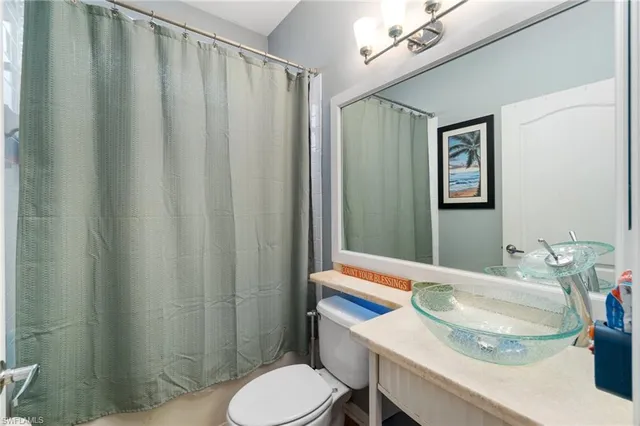 a bathroom with a sink a toilet a mirror and shower curtain