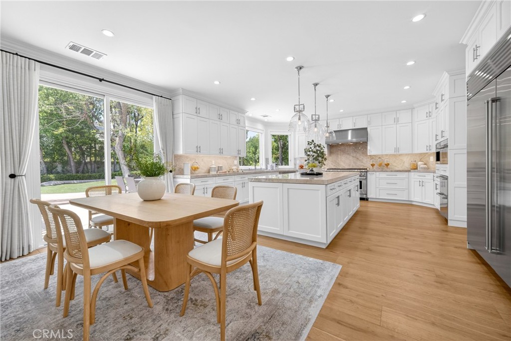 25714 Simpson Place Calabasas, CA 91302 - Photo 9 of 44 a kitchen with stainless steel appliances kitchen island granite countertop a table chairs sink and cabinets