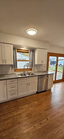 a large kitchen with stainless steel appliances wooden floor and a large window
