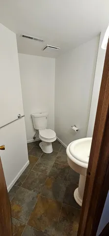 a white toilet sitting next to a bathroom sink and vanity