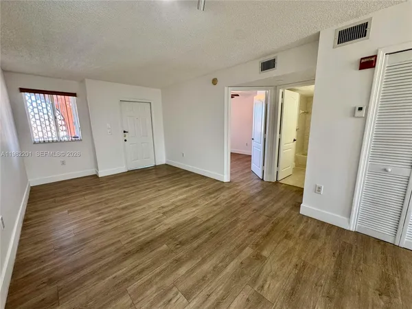 an empty room with wooden floor and windows