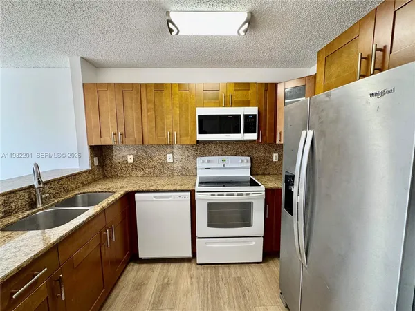 a kitchen with stainless steel appliances granite countertop a refrigerator and a sink