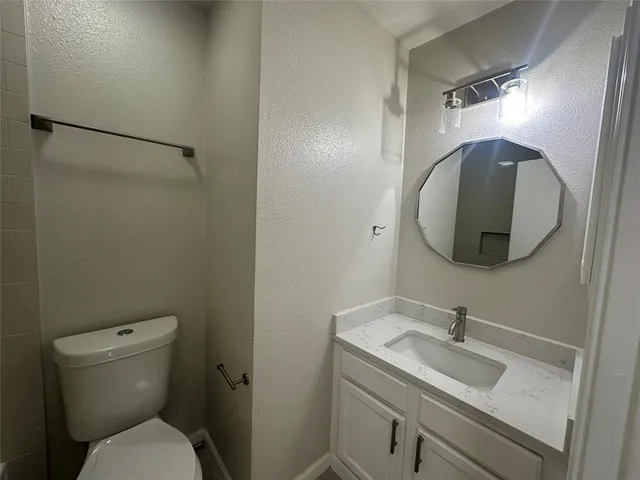 a bathroom with a toilet sink vanity and mirror