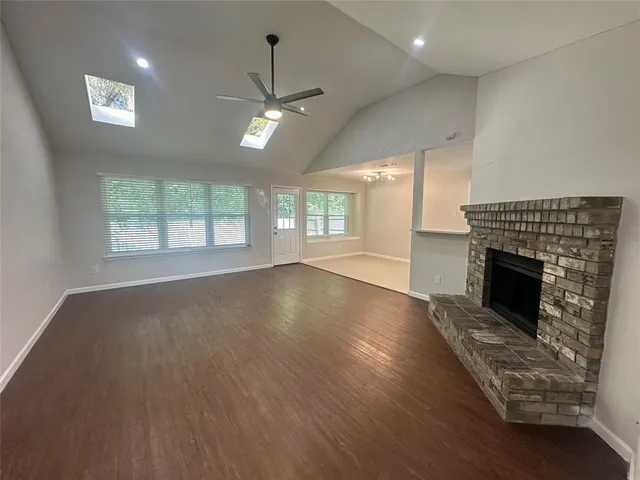 an empty room with windows fireplace and wooden floor