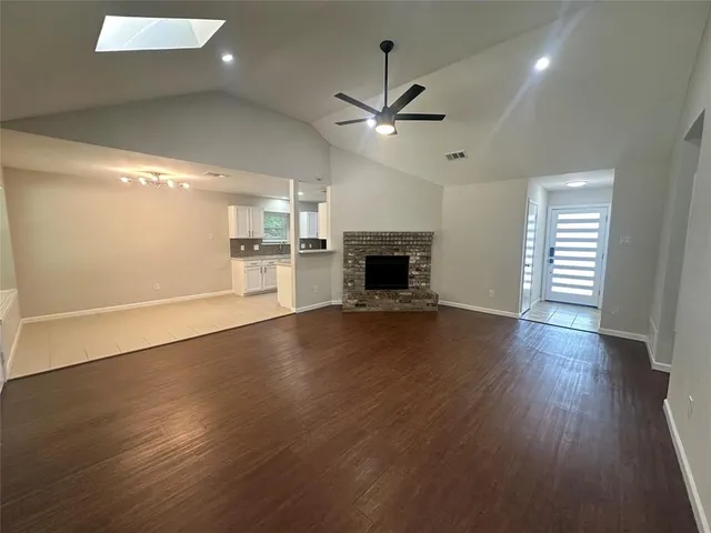 an empty room with wooden floor fireplace and windows