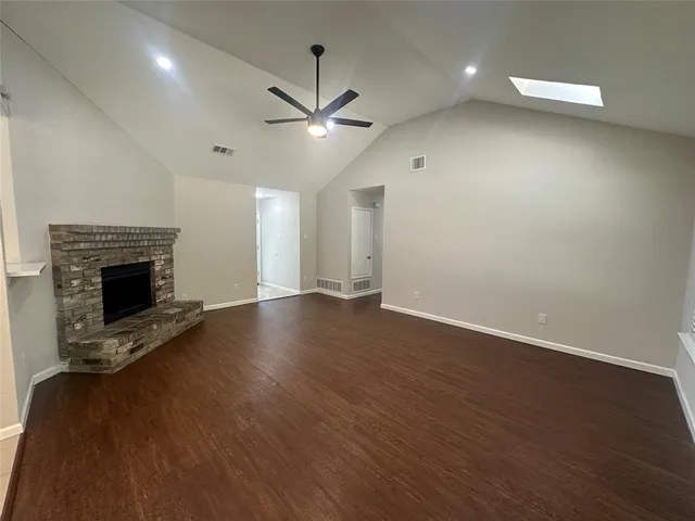 an empty room with wooden floor fireplace and windows
