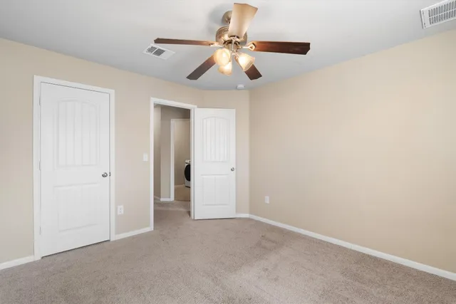 an empty room with closet and a chandelier fan