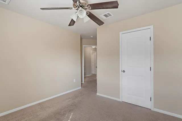 an empty room with closet and a chandelier fan